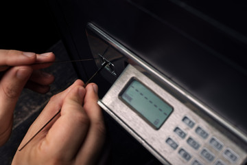 Close-up of Thief's hands attempting to Break Home Money Safe and perform Robbery.