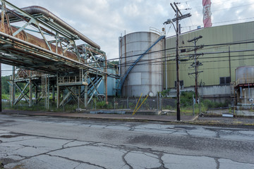 Fototapeta premium Large storage tank and empty factory with bulky pipes left abandoned