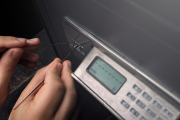 Close-up of Thief's hands attempting to Break Home Money Safe and perform Robbery.