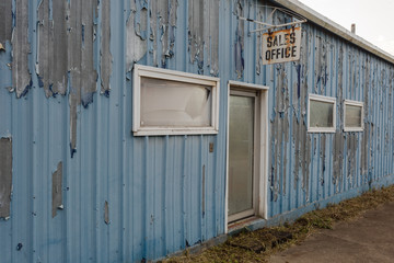 Obraz na płótnie Canvas Old tin walled blue industrial building left abandoned on empty street
