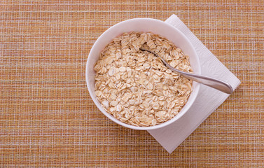 Cup with raw oatmeal on white napkin on gunny background for healthy breakfast