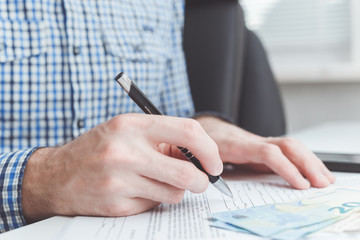 Man signing contract at office table.