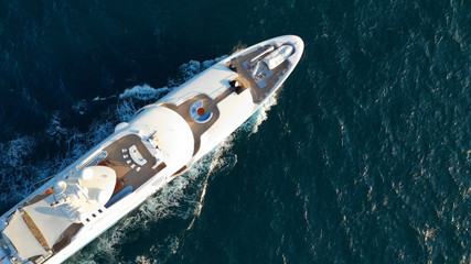 Aerial drone top view photo of luxury yacht, cruising in moderate speed in open sea with splash and wave on background