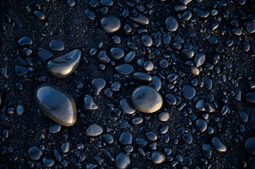 Smooth wet black pebbles on the beach