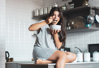 Young woman having breakfast in the kitchen