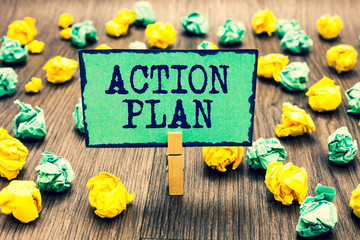 Fototapeta premium Text sign showing Action Plan. Conceptual photo list of things or schedule to be made thia current year Clothespin holding green note paper crumpled papers several tries mistakes