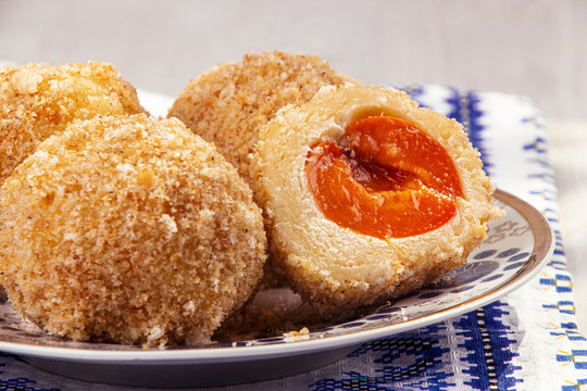 Austrian and czech sweet dessert knedle apricot dumplings on fabric with ornament background. Filled cottage cheese dough. close up