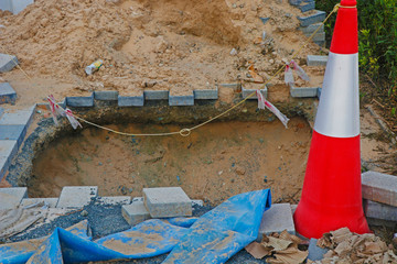 deep excavation in a foot footpath with sign pole