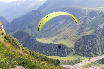 Yellow-green paraglider on a background of mountains