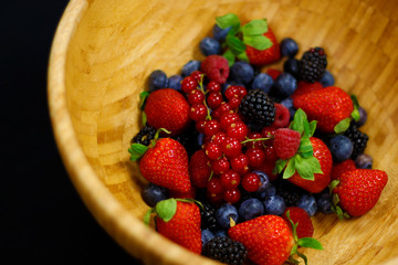 fresh berries fruit in wooden bowl includes strawberry, raspberry,blue berry,black berry etc.