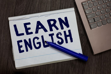 Conceptual hand writing showing Learn English. Business photo text Universal Language Easy Communication and Understand Open notebook squared page black marker computer wooden background