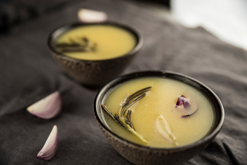 Сream soup with rosemary, potatoes and onions in brown soup plates.