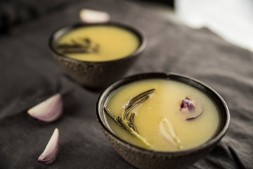 Сream soup with rosemary, potatoes and onions in brown soup plates.