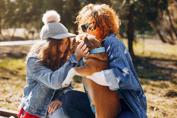 Beautiful girls in a park. Stylish women in a jeans jacket. Ladies with a dog. Mother with a daughter