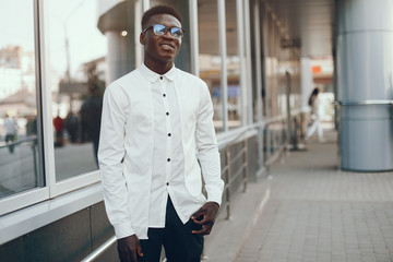 Fototapeta premium Handsome black man in a city. Businessman in a white shirt