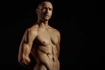 Fototapeta premium Handsome sport sexy stripped guy portrait for cosmetics and fitness drops on isolated black background