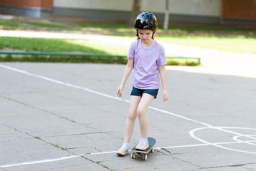Little beautiful girl rides a skateboard