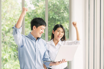 Obraz na płótnie Canvas Excited Asian couple celebrate success with laptop
