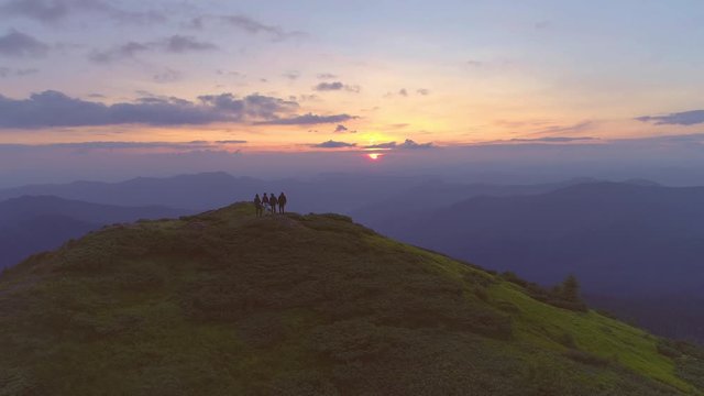 The flight above four people on the mountain top against the sunrise