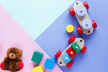 Kids toys: pyramid, wooden blocks, bear, train frame on colored background. Top view. Flat lay. Copy space for text	