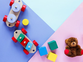 Kids toys: pyramid, wooden blocks, bear, train frame on colored background. Top view. Flat lay. Copy space for text