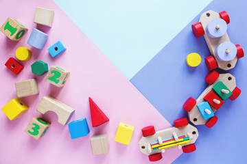 Kids toys: pyramid, wooden blocks, bear, train frame on colored background. Top view. Flat lay. Copy space for text	