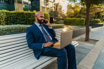Obraz premium Indian businessman holding mobile phone wearing blue suit and using modern smartphone near office. Business concept