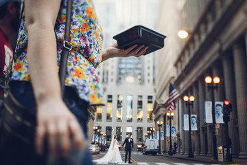 Obraz premium Elegant bride in a white dress and veil. Handsome groom in a blue suit. Couple in a big city