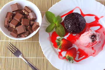 petit gateau with ice cream on white plate with strawberry over rustic wooden table