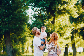 Fototapeta premium Beautiful red-haired woman with her husband and a wonderful son on a summer park