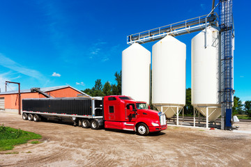 Bright Red Semi Truck by White Grain Storage Silos