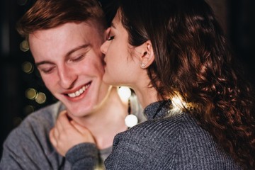  couple in love on the bed takes cover with a blanket and laughs in winter evening