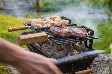 Steak and Scallops grilling on a hibachi as hot charcoal develops smoke and flames on a summer night
