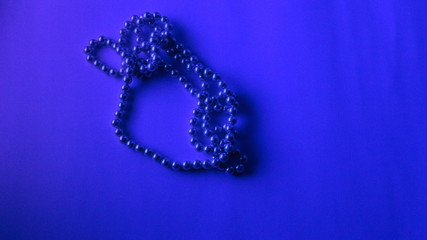 pearl necklace below neon light. With copy space to insert text. Wide screen, flat lay view. It represents youth, vanity, luxury, wealth