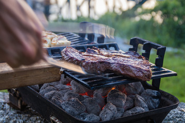 Steak and Scallops grilling on a hibachi as hot charcoal develops smoke and flames on a summer night
