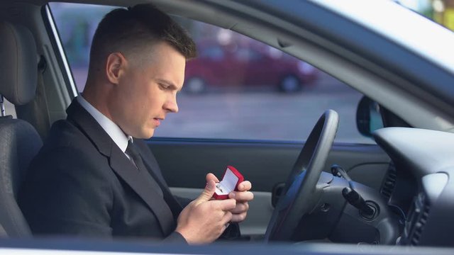 Handsome man holding box with engagement ring and deciding to make proposal