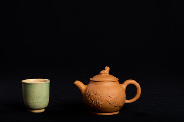 A beautiful teacup ready for morning ritual, with a lovely clay teapot.