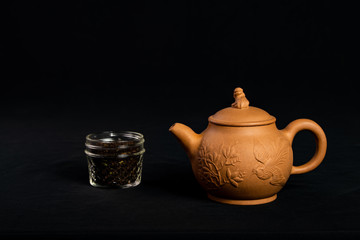 A tea pot and a small jar of tea isolated on a black background