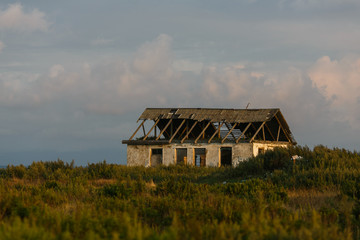Obraz premium Old abandoned house with broken windows and a roof among tall grass