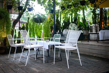 White chairs and table set outdoor coffee shop in the green garden