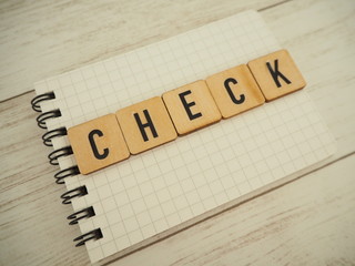 ノートの上に木製ブロックでチェックの単語