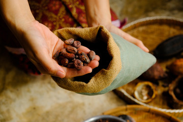 Hands of young woman holding cocoa beans with burlap sack