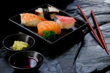 Sushi set with chopsticks,soy sauce and wasabi on black stone table