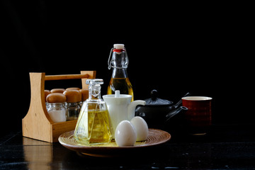 Seasoning set,olive bottles and teapot with cup on black background