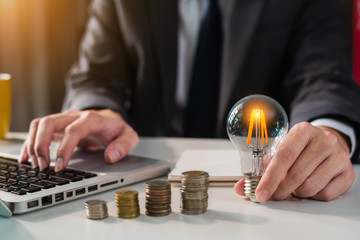 Businessman carry light bulbs with the idea of saving money, working with laptops and tabs at work in office.