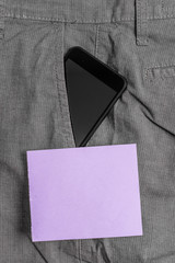 Smartphone device inside formal work trousers front pocket near note paper