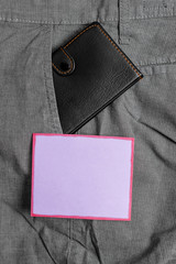 Small little wallet inside man trousers front pocket near notation paper