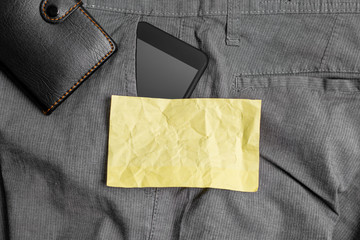 Smartphone device inside trousers front pocket with wallet and note paper