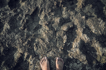 Feet woman standing on crack ground , Drought and crisis of environment.