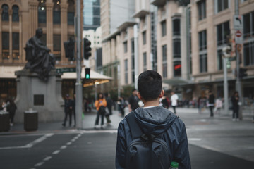 Young man with headphones in waiting to cross the road in the city.